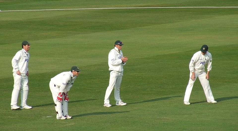 Cricket game scene with players on the field.