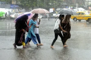 Kolkata city during monsoon rain with cars and pedestrians carrying umbrellas